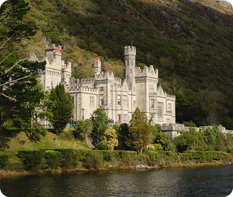Kylemore Abbey against a wooded hillside beside a calm river in Connemara, County Galway. Kylemore Abbey against a wooded hillside beside a calm river in Connemara, County Galway.