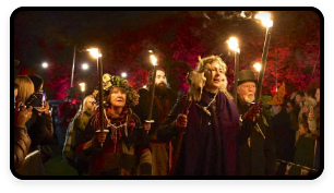A parade of people in costume walks through the night at the Puca festival.