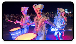 A trio of people are dressed in metallic costumes and playing drums.