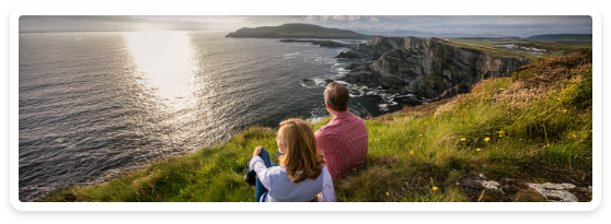 A couple sitting on a hill overlooking a body of water