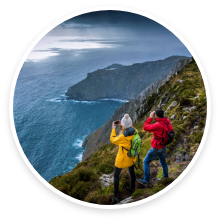 A couple hiking along a cliff that overlooks an ocean